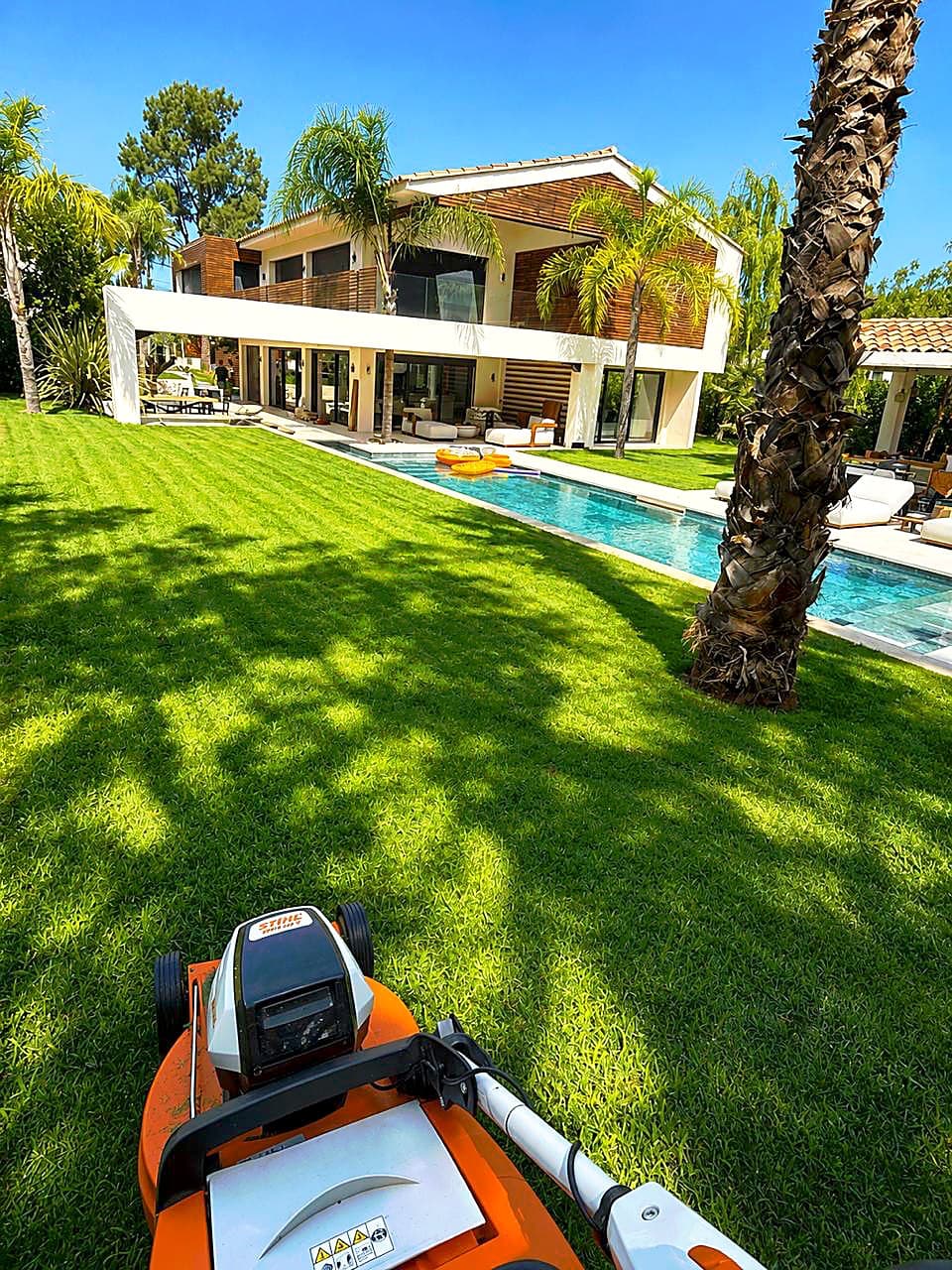 Villa contemporaine, sa piscine et sa pelouse tondue sous les palmiers